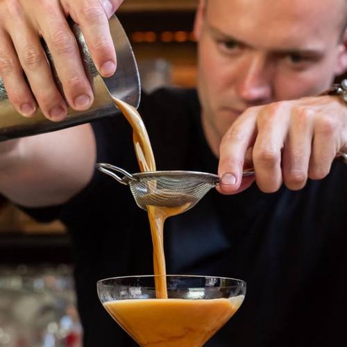 De bartender schenkt een cocktail in